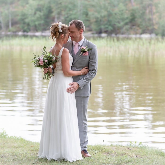 Bröllopsbilder - Brudparet poserar vid sjö